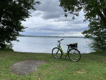 Bicycle by lake against sky