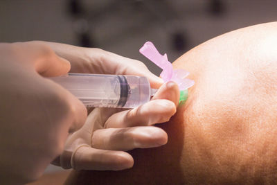 Close-up of doctor injecting patient on knee