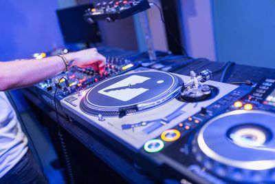 Cropped hand of male dj playing music on turntable in nightclub