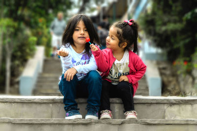 Full length of mother and girl sitting outdoors