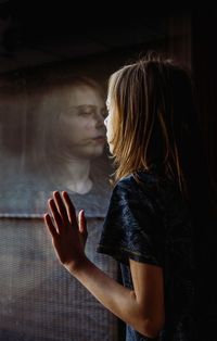 Side view of a woman standing against wall