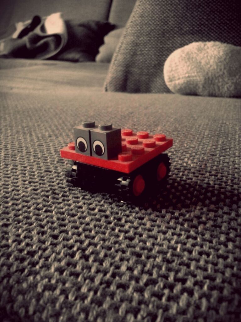 red, close-up, selective focus, transportation, indoors, still life, mode of transport, single object, focus on foreground, high angle view, toy, land vehicle, no people, car, day, stationary, part of, table, surface level, man made object