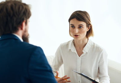 Young woman using digital tablet while standing against white background