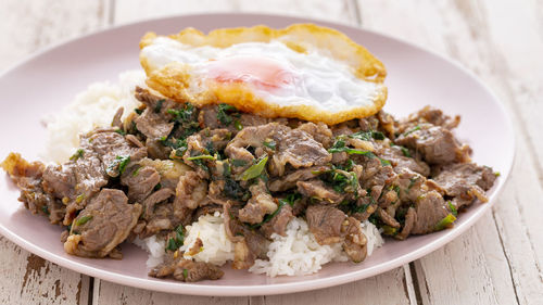 Streamed rice with stir fried beef with tree basil leaves, pepper, garlic, chili and fried egg