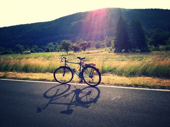 Bicycle on road amidst field against sky