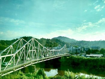 Bridge over river against cloudy sky