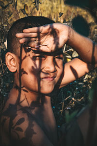 Close-up of shirtless boy shielding eyes