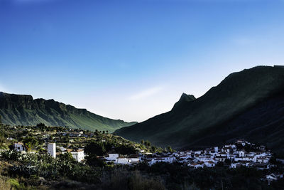 Scenic view of mountains and buildings against blue sky