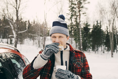 Full length of young man wearing hat against trees during winter