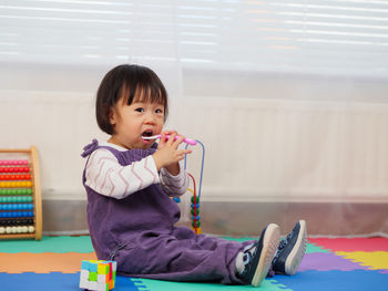 Portrait of cute baby girl brushing teeth at home