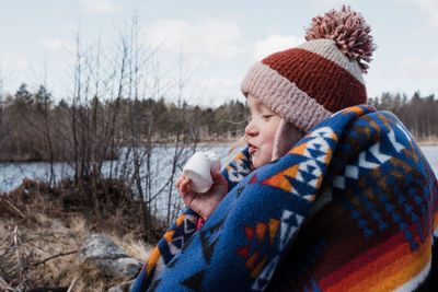 Young girl wrapped in a blanket eating a marshmallow whilst camping