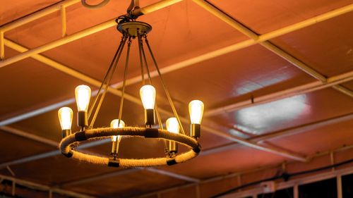 Low angle view of illuminated light bulbs hanging from ceiling