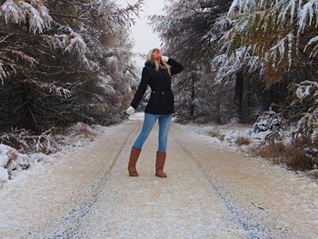 Young woman looking up while standing amidst snow covered trees