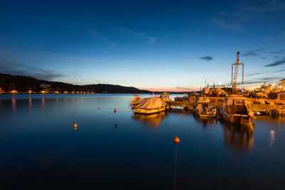 Boats moored at harbor against blue sky