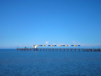 Pier over sea against clear blue sky