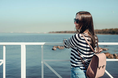 Beautiful young woman with a backpack on a background of the sea. outdoors, lifestyle