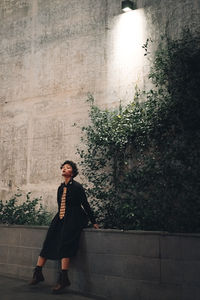 Full length of young man looking away against wall