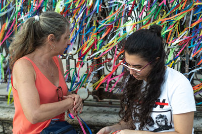 Portrait of two women placing colored ribbons on the church grid. 