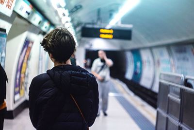 Rear view of woman standing at underground subway platform