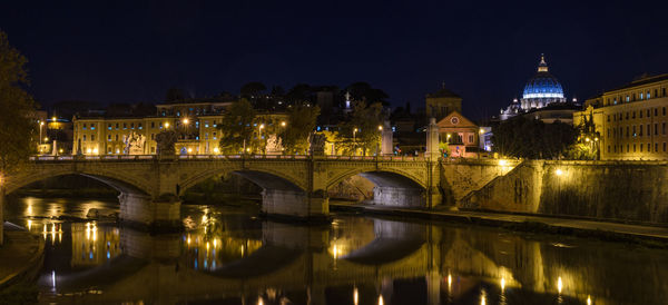 Illuminated bridge over river in city at night