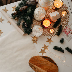 Christmas table decor, a roll of baking paper, burning white and red candles, wooden cutting board