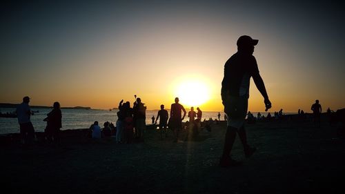 Silhouette people standing at beach during sunset