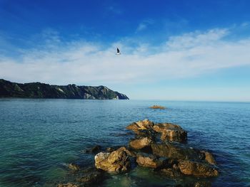 Rocks on the sea in portonovo, ancona, italy with conero and cloud sky background