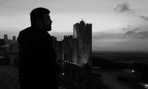 Man standing by historic castle against sky