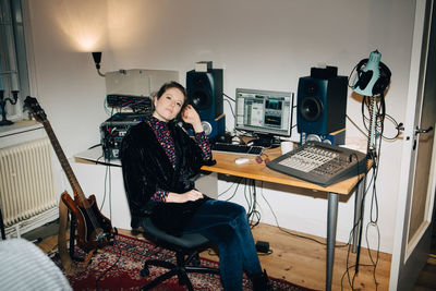 Confident young musician sitting by computer at desk in studio