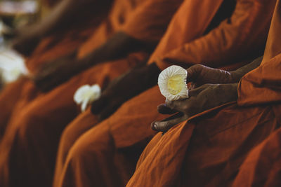 Midsection of monks holding flowers while sitting at temple