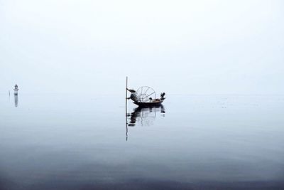 Fisherman in boat with conical fishing net