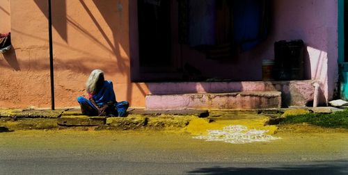 Full length of man sitting at temple outside building