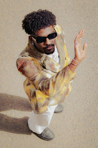 Portrait of young man wearing sunglasses against wall