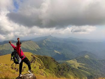 Rear view of man standing on mountain against sky