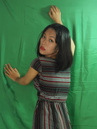 Portrait of a girl standing against green wall