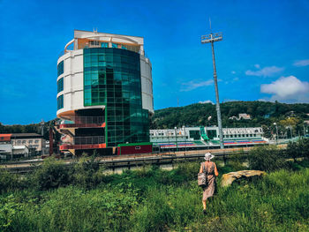 Rear view of man standing by building against sky