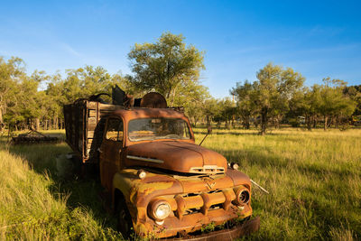 Abandoned truck in a field against the sky