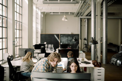 Businessman and businesswoman working on computer at workplace