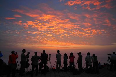 Silhouette of people taking photographs at sunset