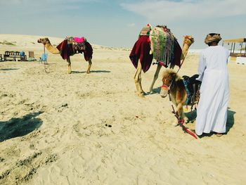 Rear view of people walking on sand