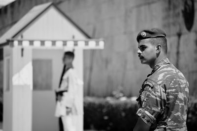 Side view of man looking away against building