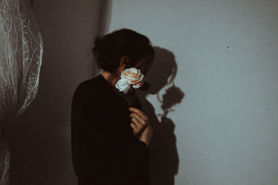 Woman standing with roses against wall at home