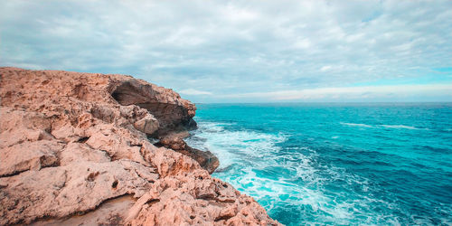 Scenic view of rocks in sea against sky