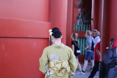 Rear view of people standing by red wall