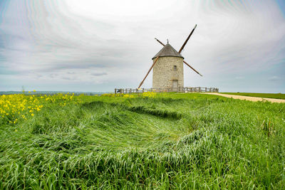 Traditional windmill on field against sky