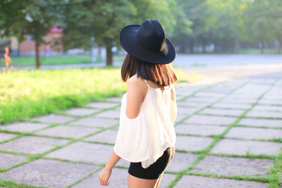 Rear view of woman standing on footpath