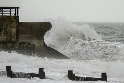 Waves splashing on shore against sky