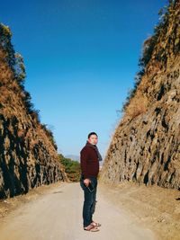 Full length portrait of young man standing against clear blue sky