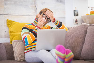 Midsection of man using mobile phone while sitting on sofa at home