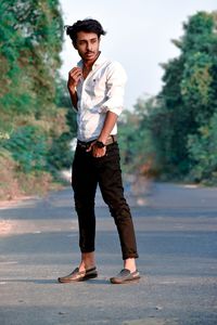 Full length portrait of young man standing on road